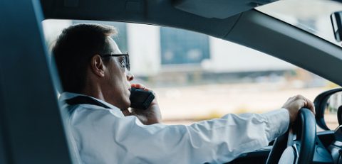 side view of mature policeman in sunglasses talking on radio set in car